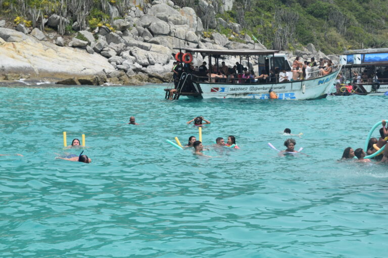 imagem de várias pessoas nadando no mar em volta do barco do passeio de barco
